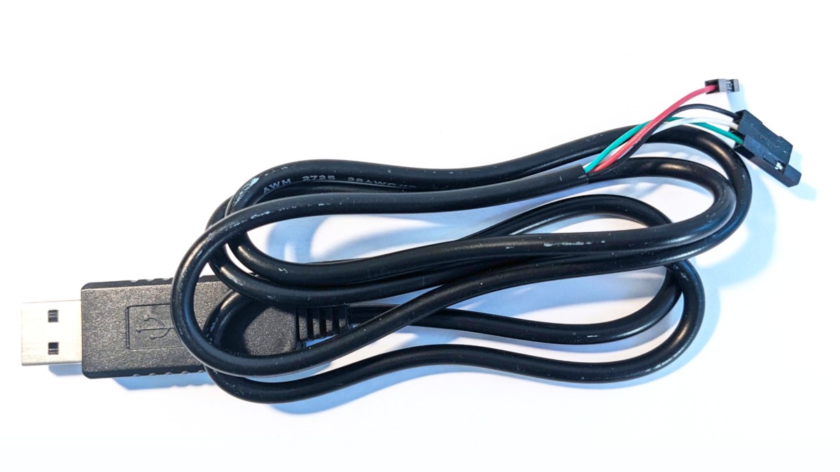 A close-up of a typical USB UART adapter, showing the USB end on the left, and the "tails" with the female DuPont connectors on the right. The tails have the common colors, red, black, white, and green.